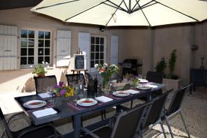 a long table with chairs and an umbrella at Maison d'hôtes de Charme Les Bruhasses in Condom