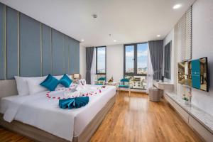 una camera da letto con un grande letto bianco con pareti blu di Calix Hotel Da Nang Beach a Da Nang
