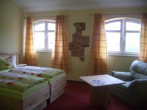 a bedroom with a bed and a couch and windows at Landhotel zum Honigdieb in Ribnitz-Damgarten