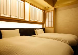 two beds sitting in a room with windows at Awaji Hamarikyu Takumi in Minamiawaji
