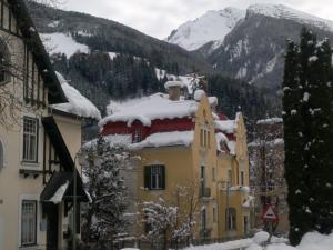 ein schneebedecktes Gebäude mit Bergen im Hintergrund in der Unterkunft Villa Karlstein in Bad Gastein