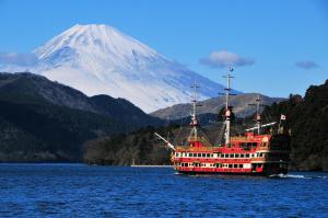 a red boat on the water with a mountain in the background at Merveille Hakone Gora in Hakone