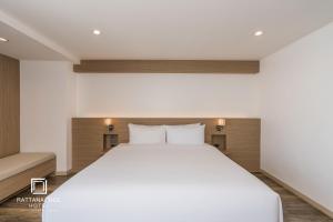 a bedroom with a large white bed with two pillows at Rattanachol Hotel in Chon Buri