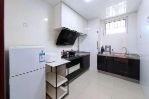 cocina blanca con nevera y fregadero en Tianjin Xiqing·University Town·, en Tianjin