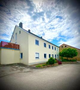 ein großes weißes Gebäude mit wolkigem Himmel im Hintergrund in der Unterkunft Bauernhaus am Limes in Altmannstein