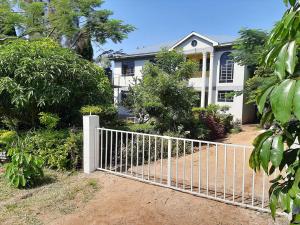 a white fence in front of a white house at Hilda Blooms in Kisumu