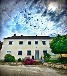 une grande maison blanche avec un ciel nuageux dans l'établissement Bauernhaus am Limes, à Altmannstein