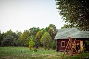 a wooden cabin in a field next to a forest at Domek z bali Roztocze in Sieniawa