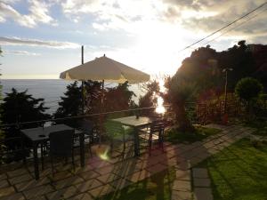 a patio with tables and an umbrella and the ocean at Corte Del Gallo in Corniglia