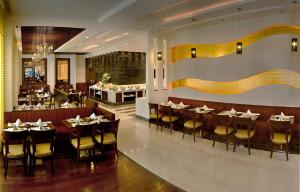 un restaurante con mesas y sillas y un bar en Park Inn Gurgaon, en Gurgaon