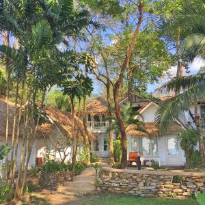 une maison blanche avec des arbres devant elle dans l'établissement Saffron On The Sea Resort, à Ko Chang