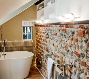 a bathroom with a white tub and a brick wall at The Grove Cromer in Cromer