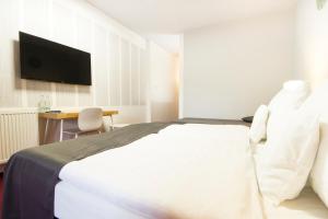 a bedroom with a large white bed and a desk at Hotel Maroli Mikulov in Mikulov