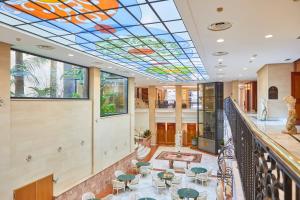 una hall con soffitto in vetro colorato, tavoli e sedie. di Bordoy Continental Palma a Palma de Mallorca
