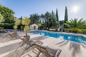 a swimming pool with two lawn chairs and trees at La Bastide de Font Clarette in Six-Fours-les-Plages