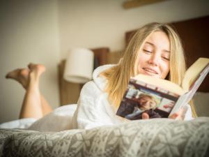 a woman laying in bed reading a book at Real Wood Pemont Myholidaylivigno in Livigno