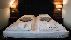 uma cama branca com toalhas e almofadas em Hotel Nad Stawem em Skalbmierz
