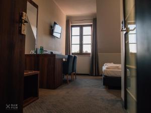 a hotel room with a desk and a bed and a window at Hotel Nad Stawem in Skalbmierz