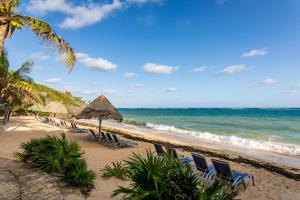 a beach with chairs and umbrellas and the ocean at VILLA ROA in Roatan