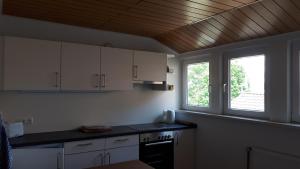 cocina con armarios blancos y estufa negra en Pension Auetal, en Döhle