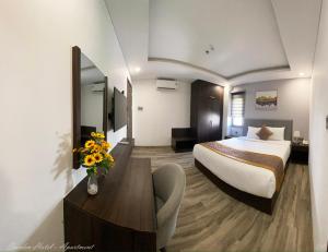 SWEDEN HOTEL and APARTMENT في دا نانغ: غرفة في الفندق بها سرير و مزهرية من الزهور
