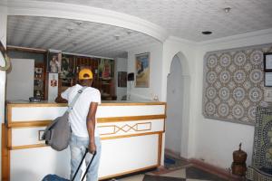 Un uomo in piedi al bancone in una cucina di Hotel Bab Sahara a Ouarzazate