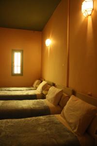 a room with three beds and a window and lights at Hotel Bab Sahara in Ouarzazate