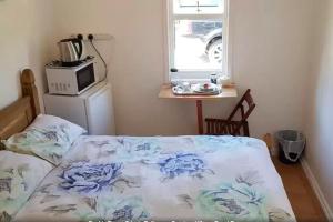 1 dormitorio con 1 cama, microondas y ventana en Ottleys Guest House, en Theydon Bois
