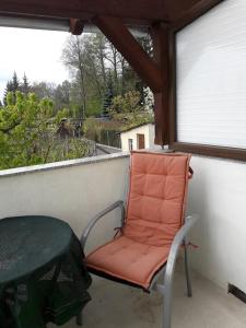 una sedia arancione seduta su un balcone con finestra di Ferienwohnung Wilke a Lübbenau