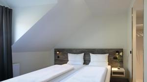 2 Betten in einem kleinen Zimmer mit weißen Wänden in der Unterkunft Dorint Resort Winterberg in Winterberg