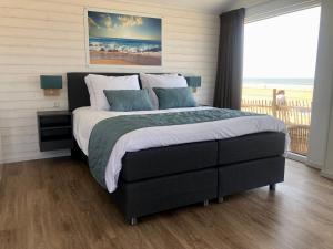 a bedroom with a large bed with a view of the ocean at STRAND 21 hotelchalets in Zandvoort