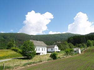 a white house in a field with mountains in the background at Byrkjeleite - modernized house with 5 bedrooms in Herand