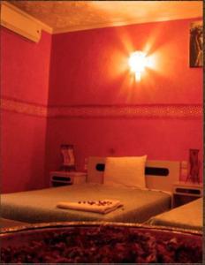una camera da letto con un letto con una luce sul muro di Hotel Bab Sahara a Ouarzazate