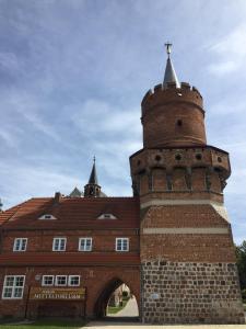 a brick building with a tower with a cross on top at Pension Mitteltorturm in Prenzlau