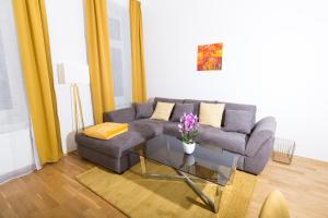 ein Wohnzimmer mit einem Sofa und einem Glastisch in der Unterkunft Rosenstein Apartments by Family & Home in Wien
