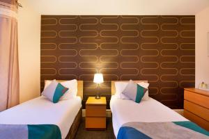 ニュートンモアにあるOYO Braeriach Hotel, Highlands Scotlandのベッド2台と壁が備わるホテルルームです。