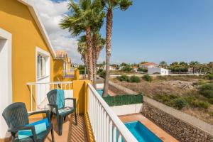 a balcony with chairs and a swimming pool and palm trees at Samuel y Benjamin in Ciutadella