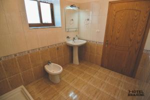 a bathroom with a sink and a toilet and a mirror at Hotel Brahimi in Gjirokastër