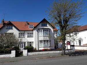 ein weißes Haus mit einem Baum davor in der Unterkunft Seren Villa in Llandudno