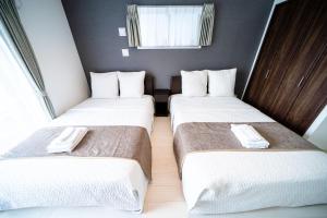 2 Betten in einem Hotelzimmer mit weißer Bettwäsche in der Unterkunft Roof Hanazonocho-Nishi in Osaka