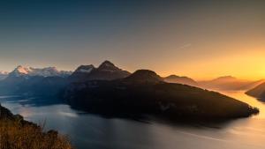 eine Insel in einem Gewässer mit Bergen in der Unterkunft Hotel Schmid & Alfa in Brunnen