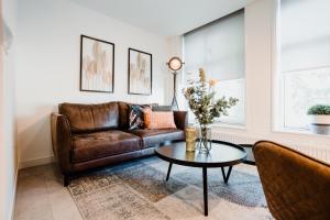 a living room with a brown leather couch and a table at De Zilte Melis in Meliskerke