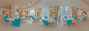 a dining room with tables and blue chairs at Dolphin Resort by Stellar Hotels, Sochi in Sochi