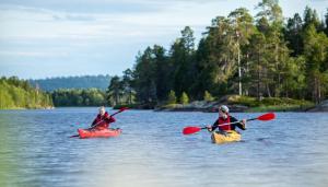 two people in kayaks in the water on a lake at Wilderness Hotel Inari & Igloos in Inari