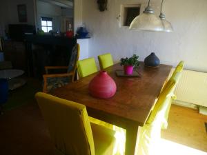 una mesa de madera con sillas amarillas y jarrones. en Au Coeur de la Cour, en Saint-Georges-sur-Cher