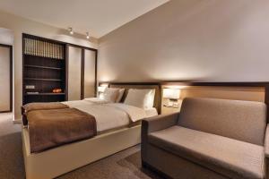 a bedroom with a bed and a chair and a couch at Hotel Bono in Budva