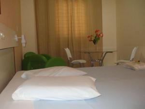 a white bed in a room with a table and chairs at Hotel Urubupunga in Ilha Solteira