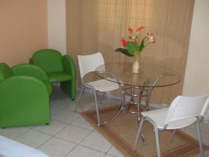 a dining room with a glass table and green chairs at Hotel Urubupunga in Ilha Solteira