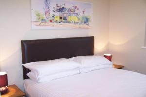 1 cama con almohadas blancas y una pintura en la pared en Metro Inns Falkirk, en Falkirk