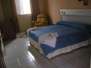 a bedroom with a bed with blue and white sheets at Hotel Urubupunga in Ilha Solteira